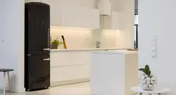 Черный холодильник на белой кухне в интерьере фото