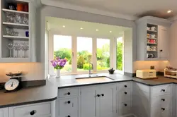 Белая кухня с мойкой у окна фото