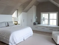 Спальня в мансарде деревянного дома со скошенным потолком фото