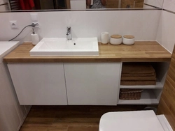 Photo of a bathtub with a sink and a bedside table in the bathroom