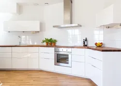 White kitchen with wooden countertop and black handles in the interior