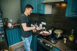Мужчына гатуе на кухні фота