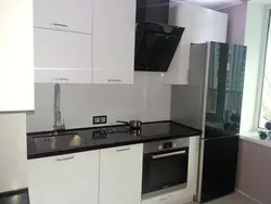 Черный холодильник на белой кухне в интерьере фото
