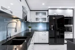 Чорны халадзільнік на белай кухні ў інтэр'еры фота
