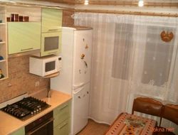 Холодильник у балконной двери на кухне фото