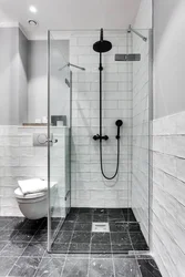 Black shower cabin in the interior of a white bath