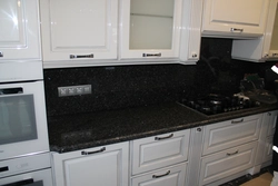 Kitchen With Black Countertop And Marbled Splashback Photo