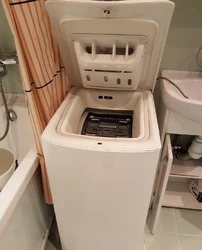 Vertical washing machine in the bathroom interior