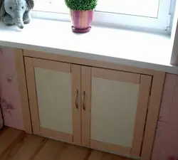 Дызайн халадзільніка пад акном на кухні ў хрушчоўцы.