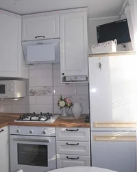 Interior of a small kitchen photo with a gas water heater and a refrigerator