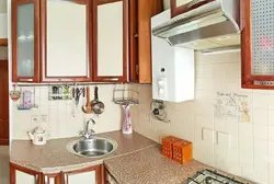 Interior of a small kitchen photo with a gas water heater and a refrigerator