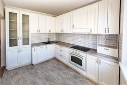 Photo of a white kitchen with wooden walls