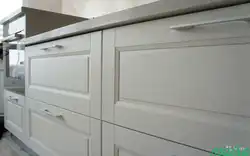 Photo of a white kitchen with wooden walls