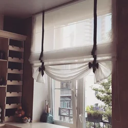 Roman blinds in the kitchen interior with tulle