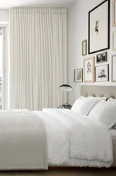 Белые стены в интерьере спальни с шторами
