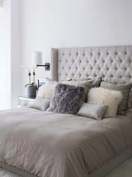 Gray bed with a soft headboard in the bedroom interior photo