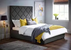 Gray bed with a soft headboard in the bedroom interior photo