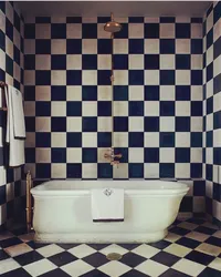 Bathtub made of white and black tiles in the bathroom photo