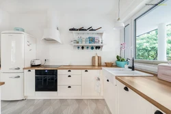 Белый гарнитур с деревянной столешницей в интерьере кухни