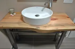 Photo of a bathtub with a sink and a bedside table in the bathroom