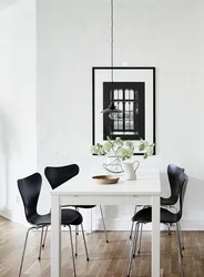 Белы стол з чорнымі крэсламі ў інтэр'еры кухні