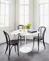 Белый стол с черными стульями в интерьере кухни