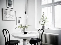 Белый стол с черными стульями в интерьере кухни