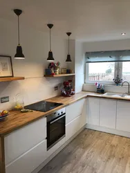 White kitchen in the interior with a wooden countertop real photos