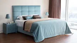 Turquoise bed in a bedroom interior with a soft headboard