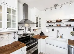 White Kitchen With Wooden Countertop And Black Handles In The Interior