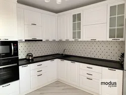 White kitchen with wooden countertop and black handles in the interior