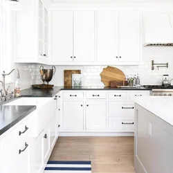 White Kitchen With Wooden Countertop And Black Handles In The Interior