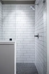 Bathtub with white tiles and gray grout photo