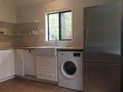 In the kitchen there is a washing machine and dishwasher photo