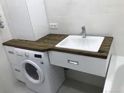 Washing machine under the countertop in the bathroom photo