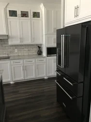 Black refrigerator in the interior of a white kitchen