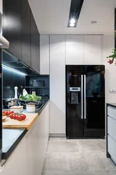 Black refrigerator in the interior of a white kitchen